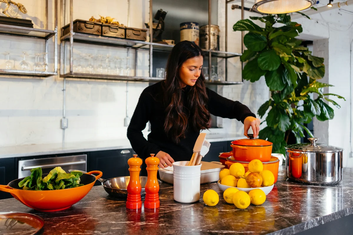 woman standing in front of fruits holding pot's lid - healthy lifestyle wellness - affordable air fryers for healthy family meals