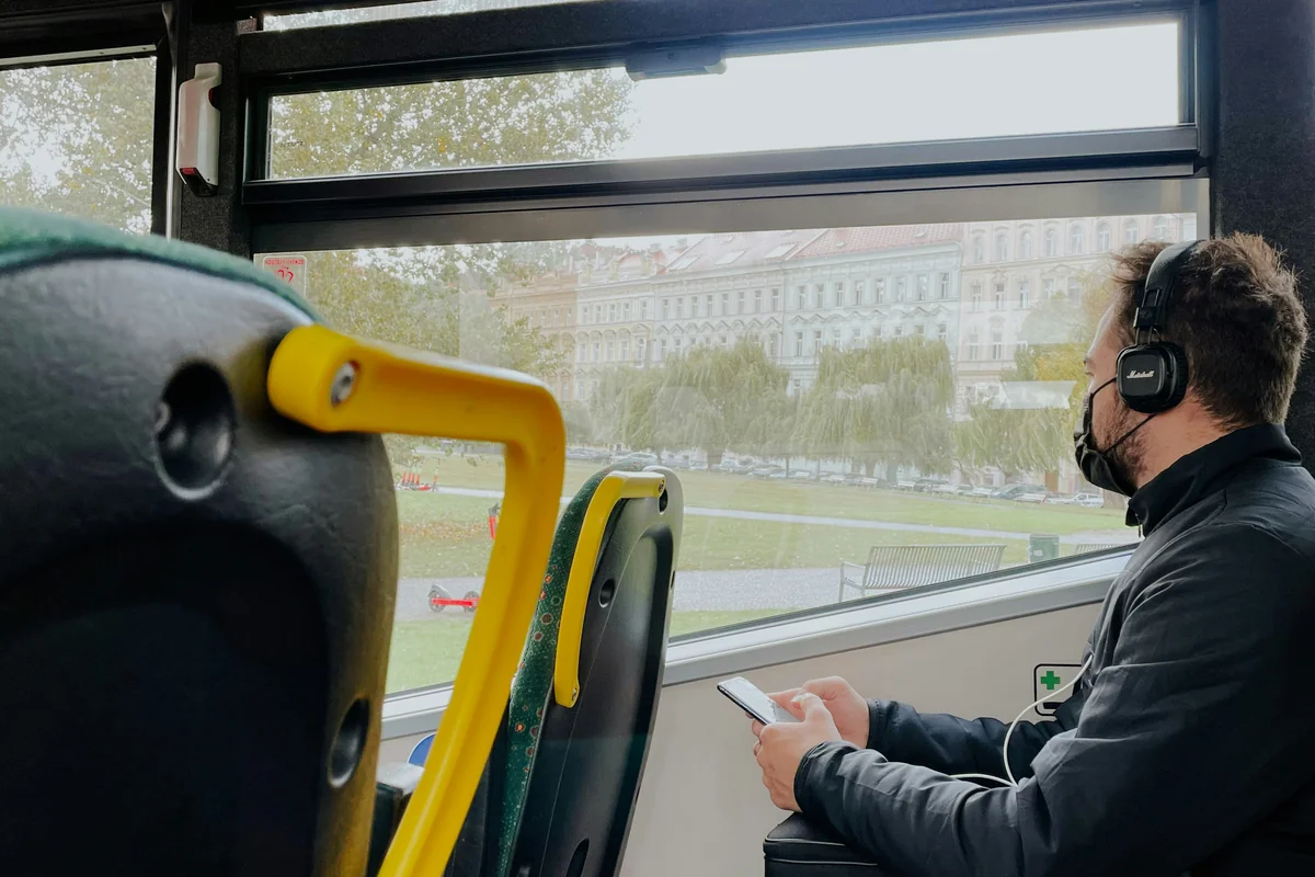 a man wearing headphones sitting on a bus - affordable noise cancelling headphones for commuting