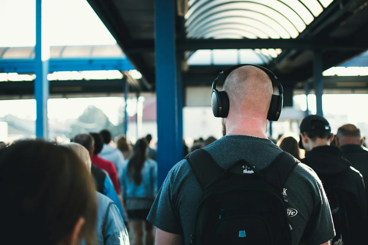 walking man wearing black wireless headphones near people - affordable noise cancelling headphones for commuting