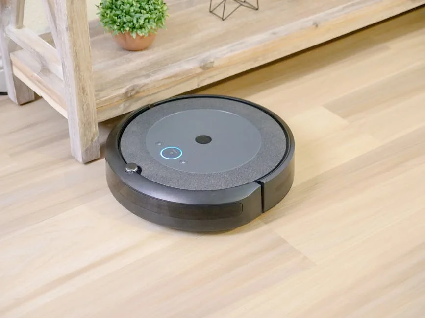 Automated robotic vacuum cleaner on hardwood floor next to plant. - affordable robotic vacuums for hardwood floors
