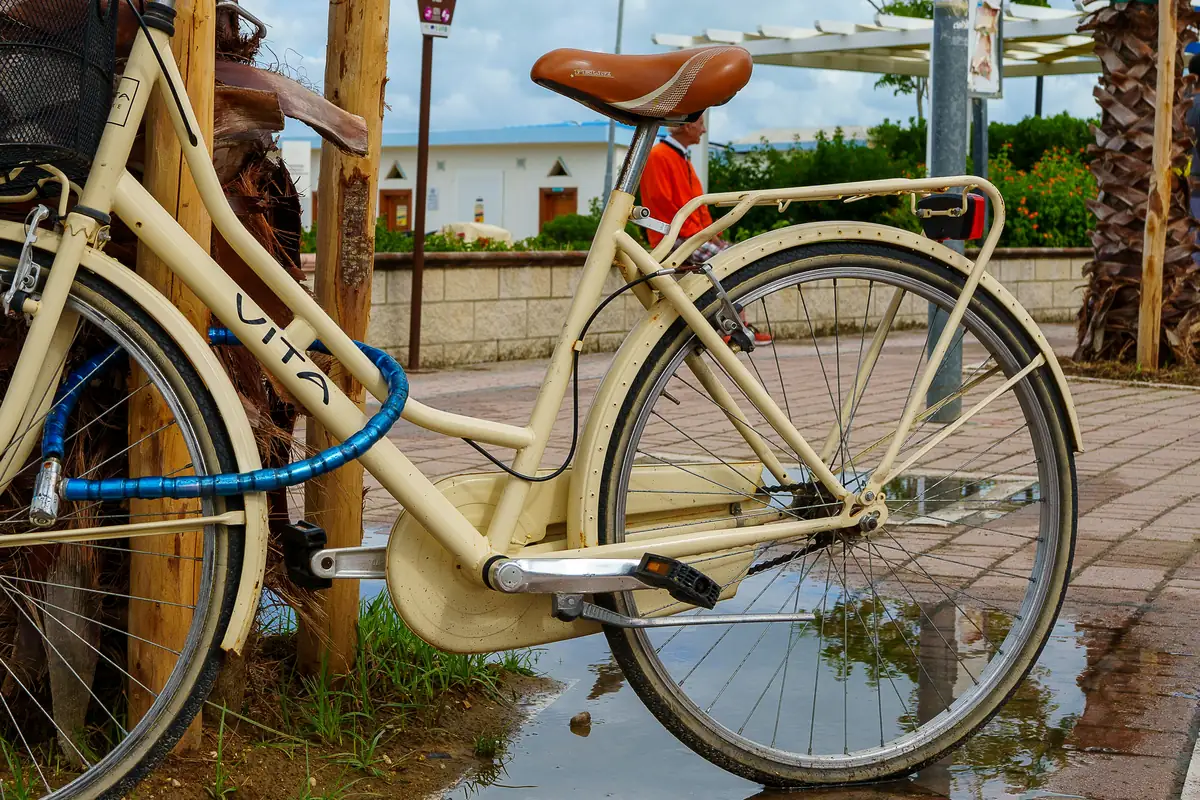 A cream-colored bicycle is locked to a post. - best bike locks for urban commuting