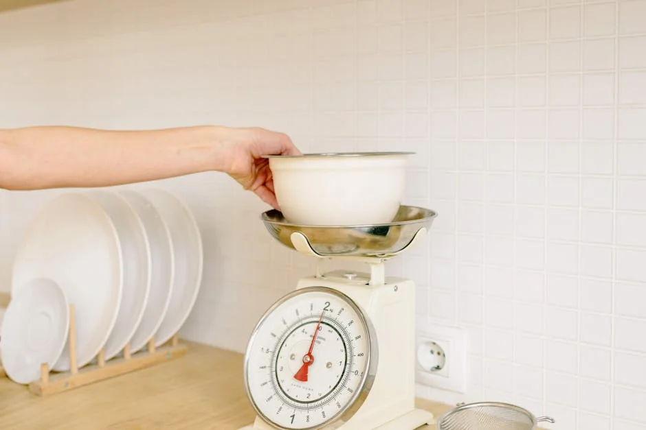 Close-up of hand placing a bowl on a kitchen weighing scale for food preparation. - best digital kitchen scales for precise baking