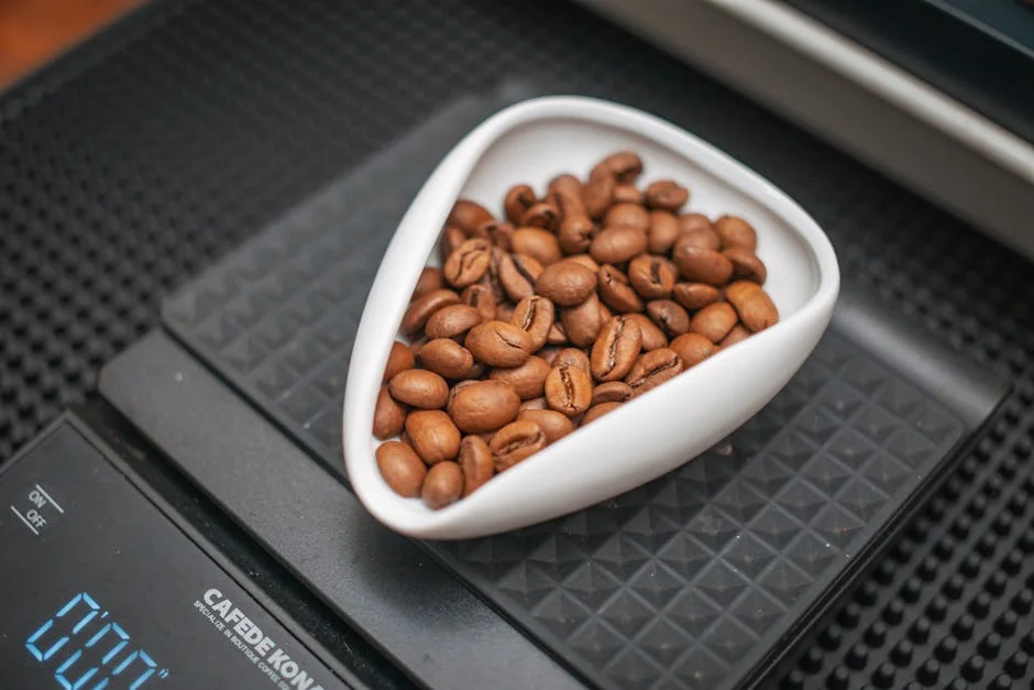A close-up image of roasted coffee beans in a white container on a digital kitchen scale, ideal for coffee preparation. - best digital kitchen scales for precise baking