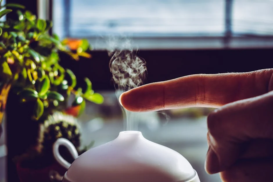 A hand touches mist rising from a diffuser, creating a relaxing ambiance indoors. - best essential oil diffusers for large rooms