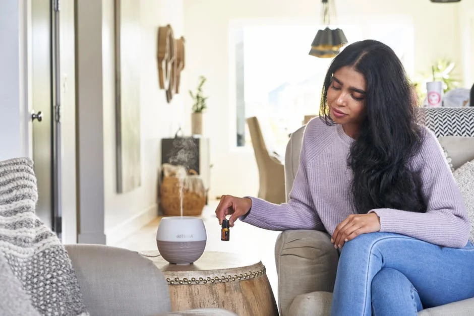 A woman in a cozy setting using an essential oil diffuser for relaxation and wellness. - best essential oil diffusers for large rooms
