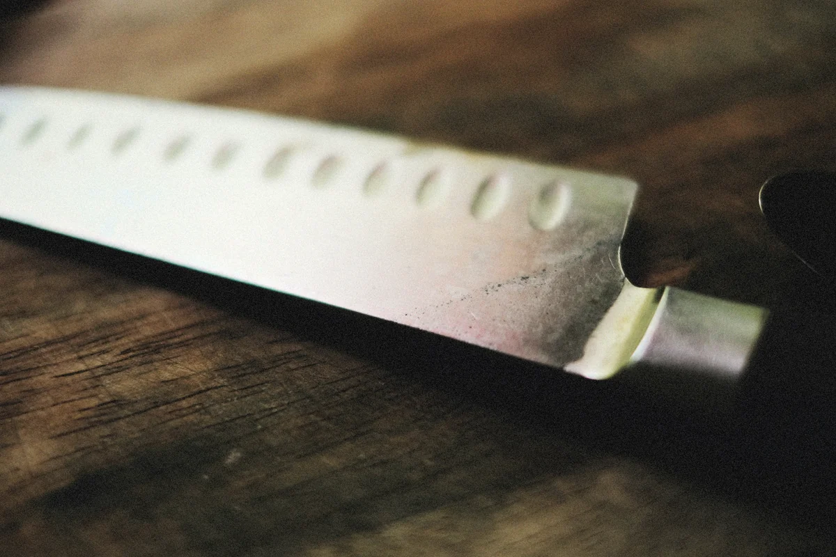 a close up of a knife on a wooden table - best kitchen knives for home chefs on a budget