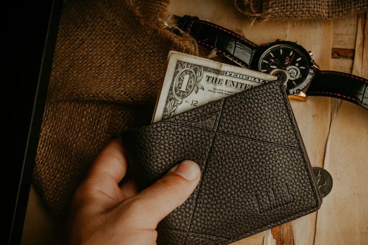 a person is holding a wallet and a watch - best minimalist wallets for men with rfid blocking