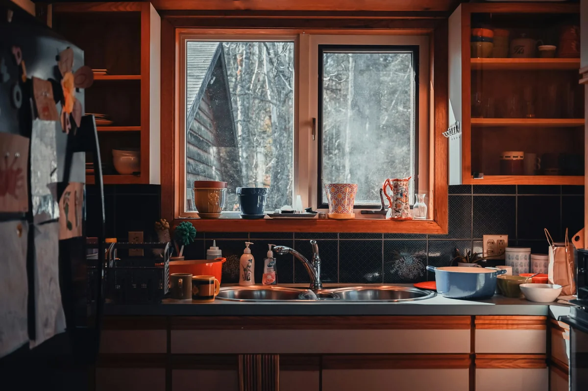 A kitchen filled with lots of clutter next to a window - best multipurpose cleaning sprays for kitchens