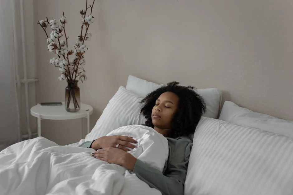 A woman resting peacefully in bed with a cozy blanket and soft pillows. - rest relaxation bedroom - best organic cotton bed sheets for hot sleepers