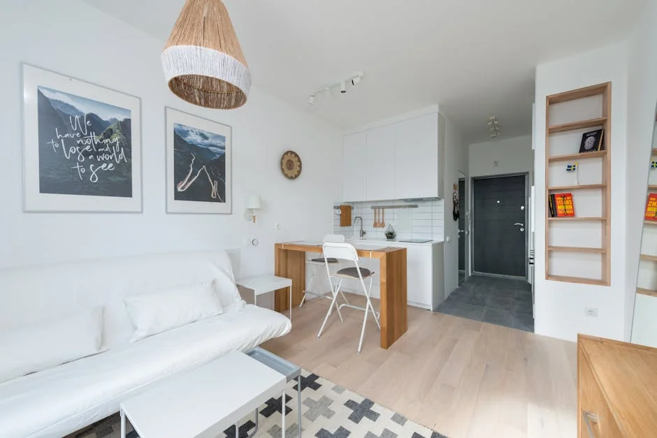 Minimalist wooden furniture in modern studio apartment with white sofa and kitchen cupboards in sunlight - best product reviews for small apartments