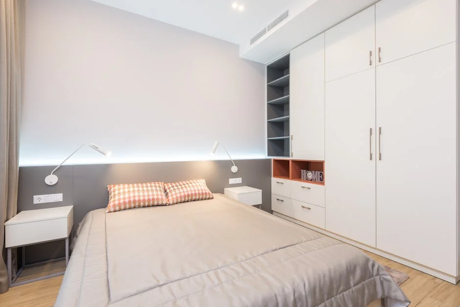 Comfortable bed with pillows placed near bedside tables and white wardrobe in modern spacious bedroom with glowing lamps in apartment - best reading lamps for bedside tables