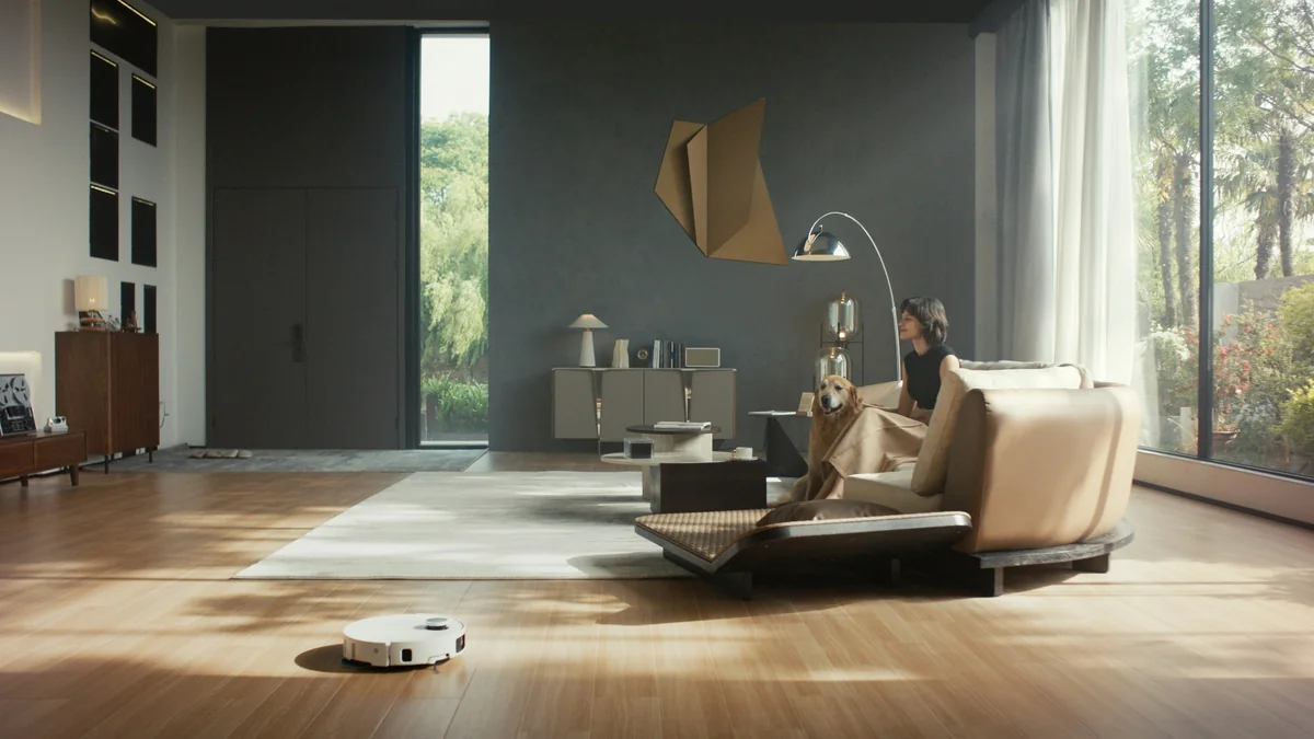 Dreame robot vacuum and mop is cleaning a spacious, modern living room as a woman relaxes with her pet dog on the sofa. - best value air purifiers for large living rooms