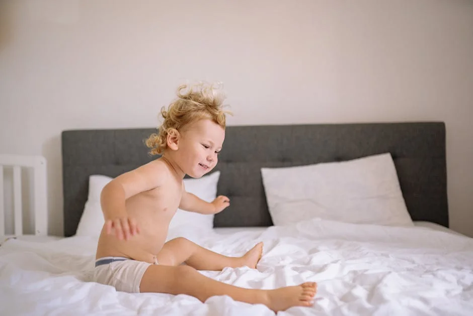 Smiling child energetically jumping on a bed in a cozy, well-lit bedroom, exuding joy. - best waterproof mattress protectors for kids