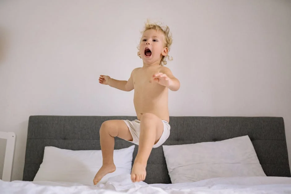 A cheerful toddler energetically jumps on a bed, expressing joy at home. - best waterproof mattress protectors for kids