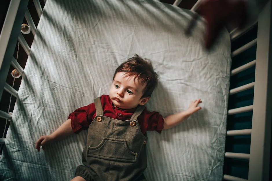 Top view of adorable toddler lying on comfortable mattress in crib and looking away - best waterproof mattress protectors for kids