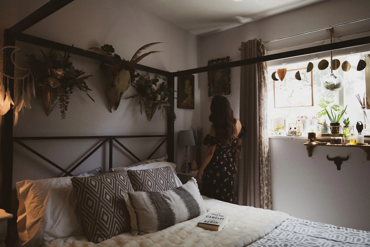 woman wearing black and red strapless dress standing besides brown curtain - rest relaxation bedroom - best weighted blankets for anxiety and sleep