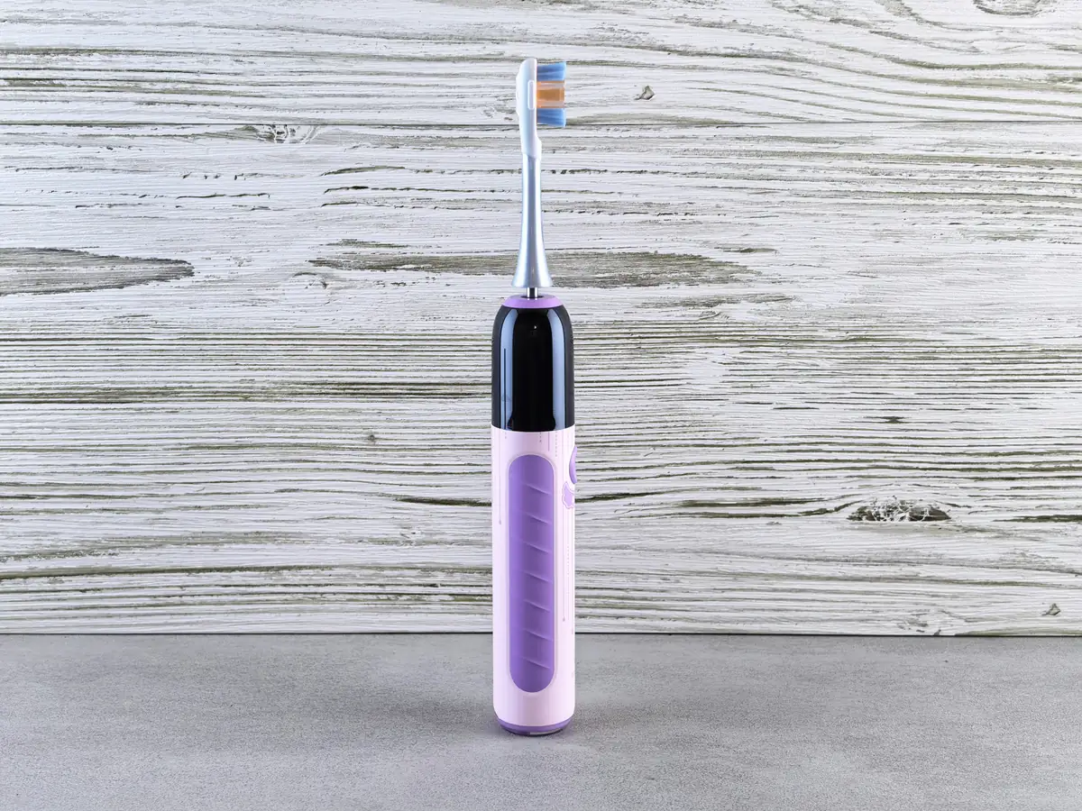 A purple electric toothbrush on a gray surface. - budget friendly electric toothbrushes with long battery life