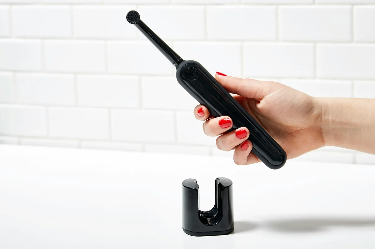 person holding black electronic device - budget friendly electric toothbrushes with long battery life