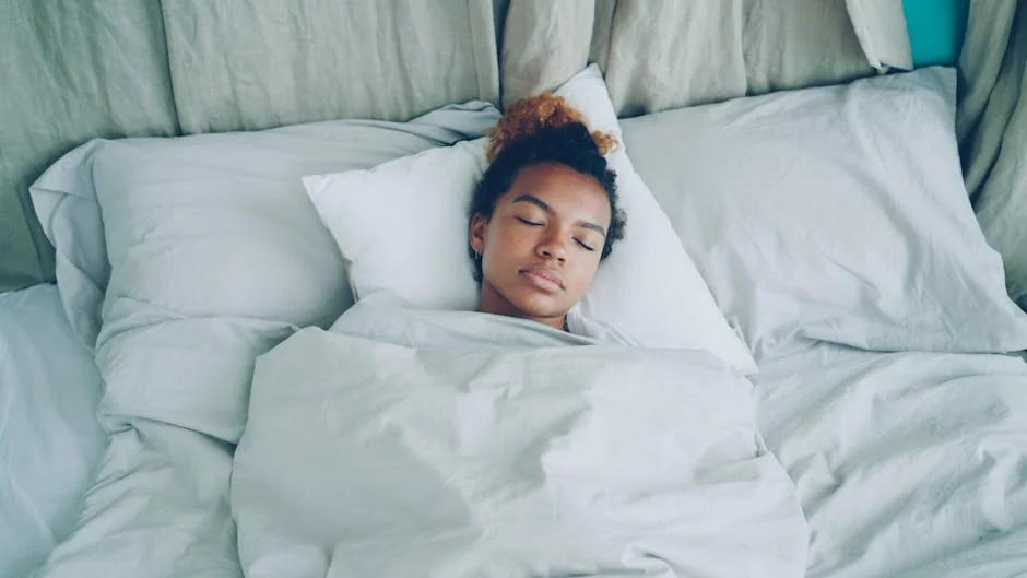 A serene woman peacefully sleeping in a cozy, white-sheeted bed. - rest relaxation bedroom - highly rated memory foam pillows for side sleepers