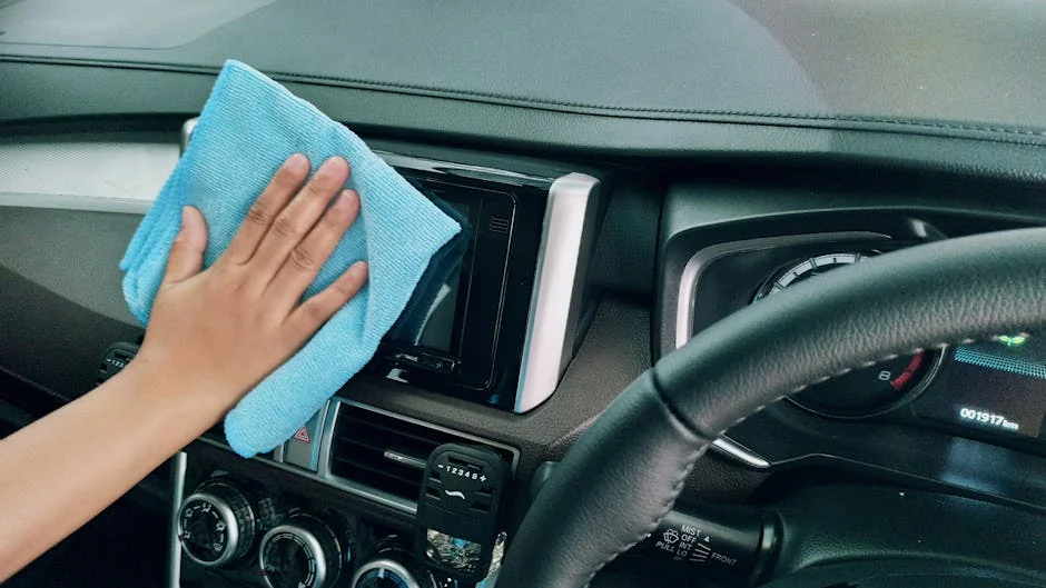 Crop anonymous person polishing panel in right hand drive car by using blue fiber cloth - most absorbent microfiber cleaning cloths
