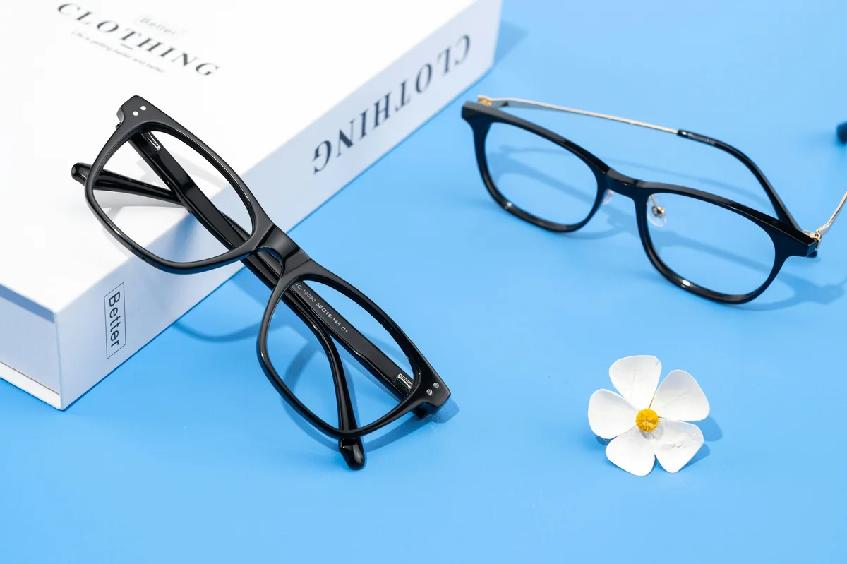 This image showcases two pairs of sleek, black eyeglasses, each with distinct designs. The left pair features a bold, classic square frame, perfect for those seeking a confident, modern look. The right pair incorporates a unique metal bridge, adding a subtle touch of elegance to its traditional round shape. - most stylish blue light blocking glasses for work