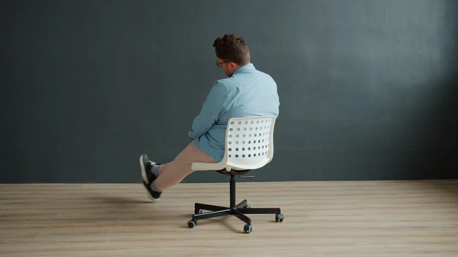 Rear view of a man spinning on a swivel chair in a minimalist interior setting. - top rated ergonomic office chairs for back pain