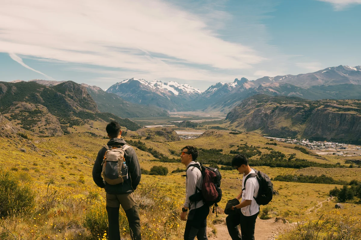 Three hikers observe a vast mountain valley landscape. - adventure vacation destination - top rated handheld garment steamers for travel