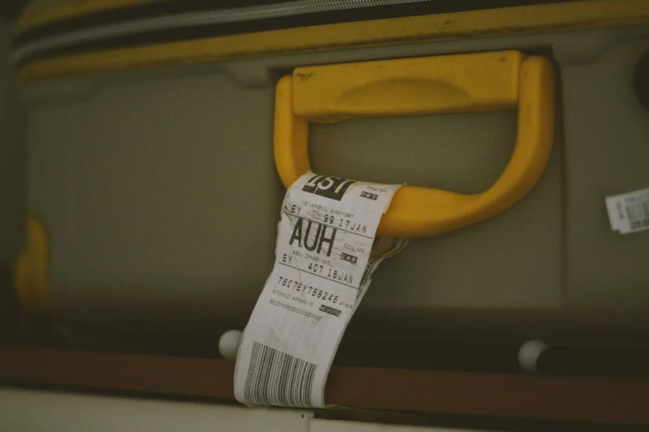 Close-up of a yellow suitcase handle with a visible travel tag and barcode, ideal for travel themes. - top rated luggage sets for frequent flyers