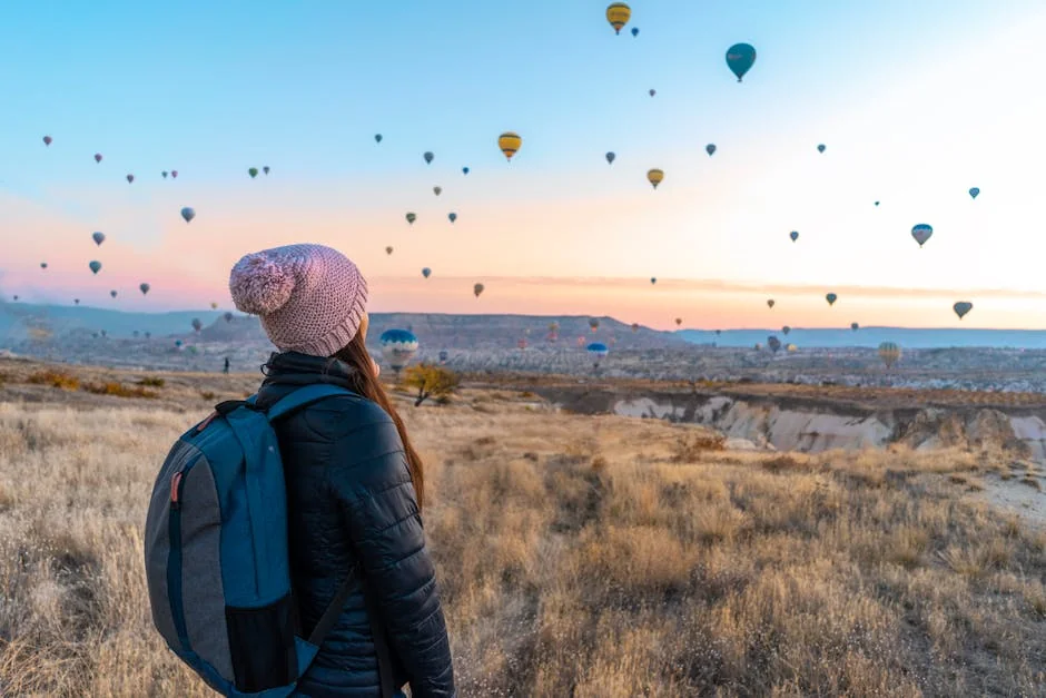 Woman watching hot air balloons in Cappadocia at sunrise, a popular travel destination. - adventure vacation destination - top rated portable power banks for travel